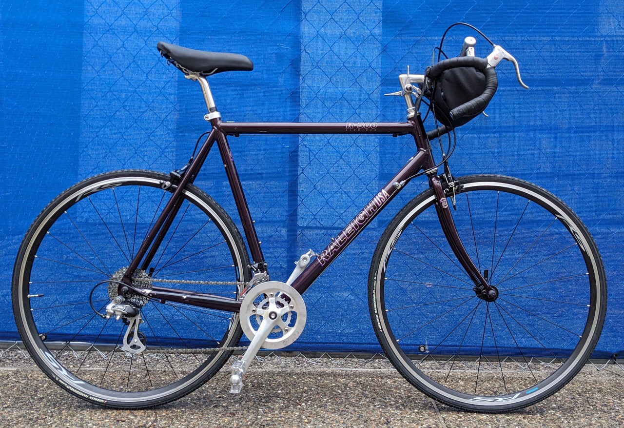 A purple raleigh R500 against a blue wall