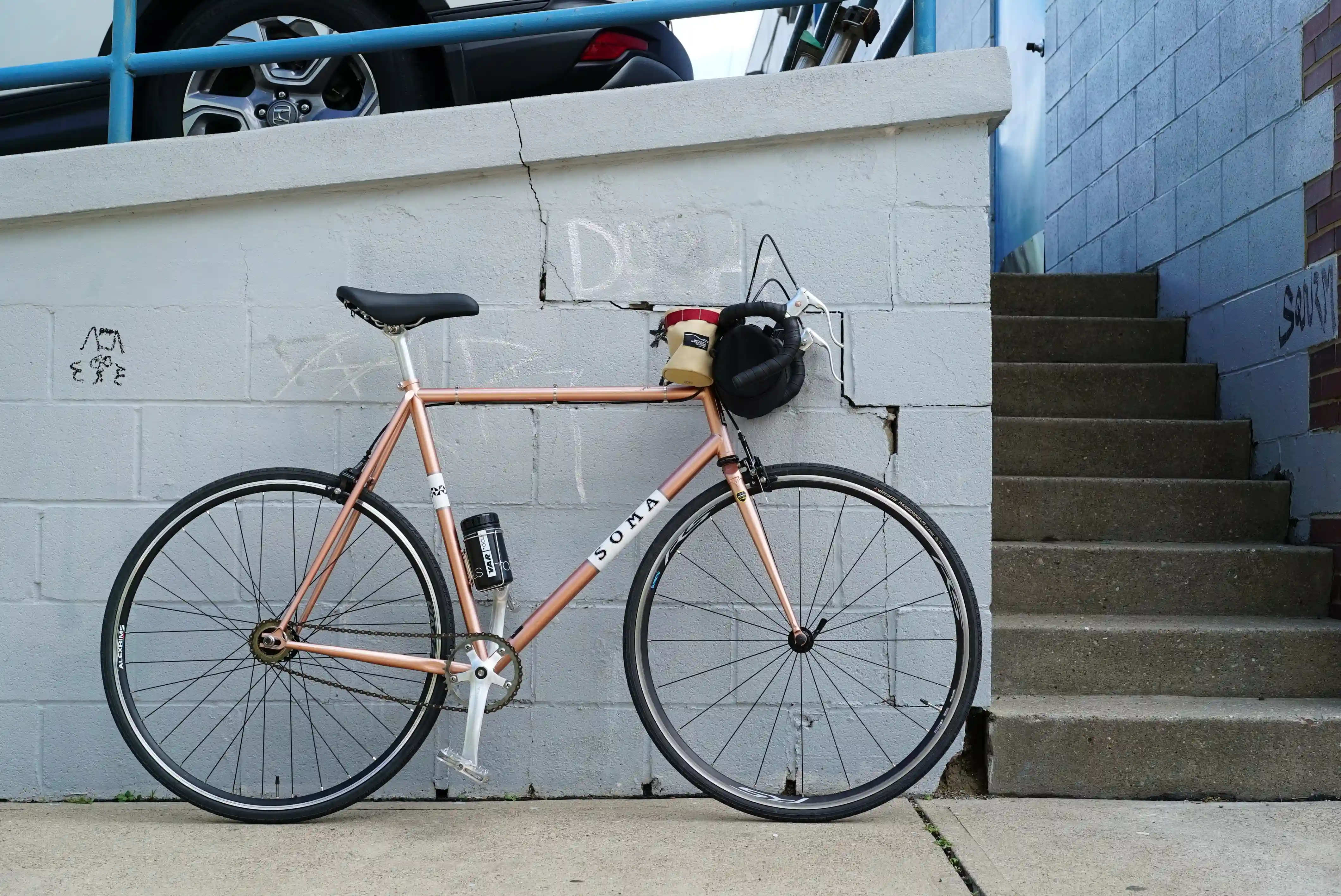 An orange Soma Rush against a pale blue-gray brick wall.